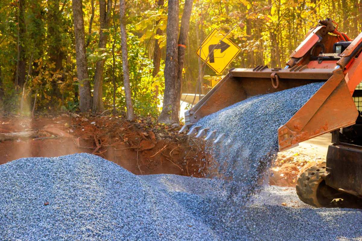 Skid steer placing gravel for backyard hardscape preparation